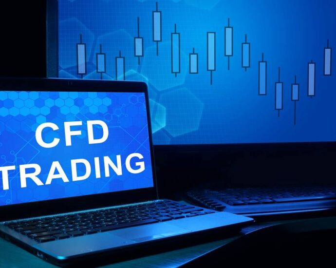 Laptop z napisem "CFD trading" na ekranie i wykres w tle